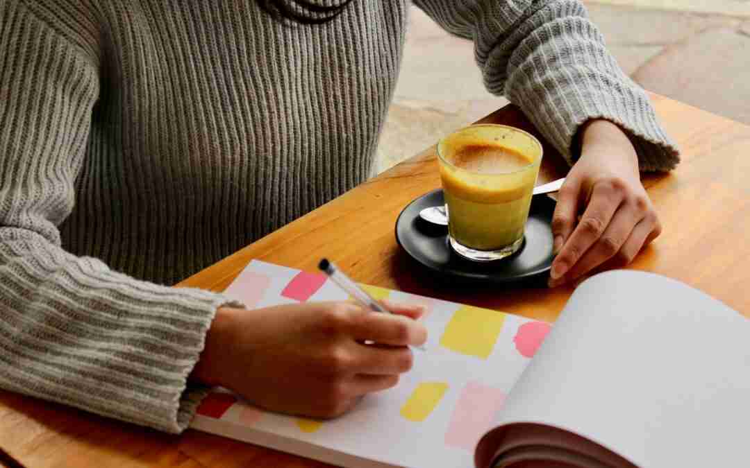 a person writing notes and drinking coffee